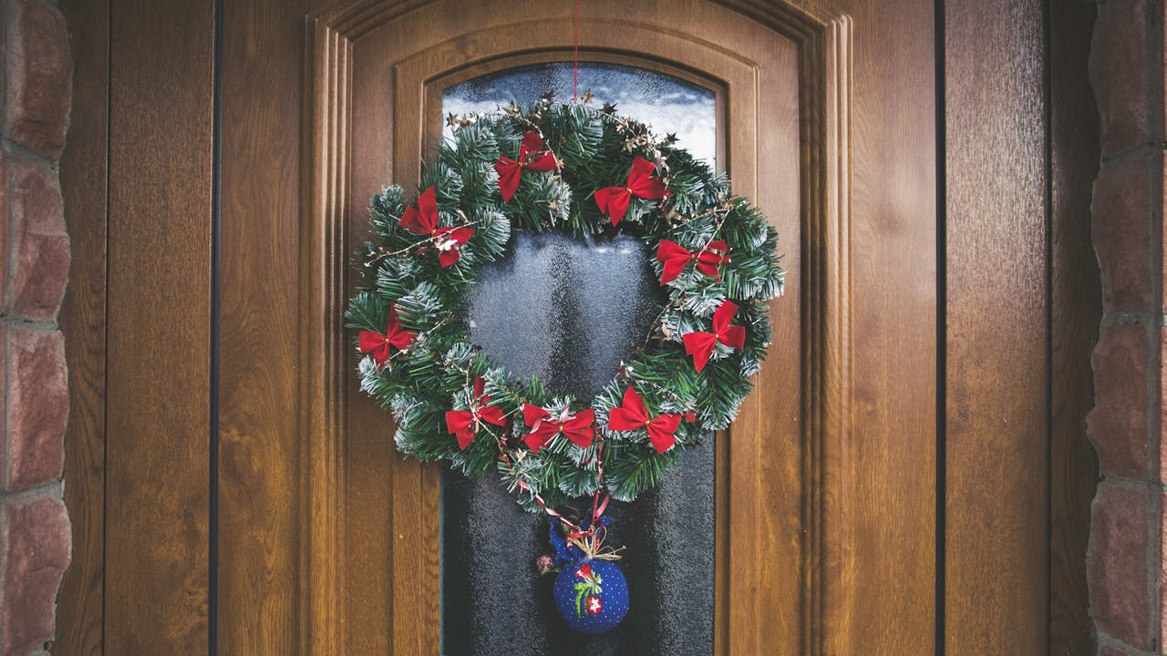 A beautifully decorated wooden door with a festive wreath and holiday ornaments.